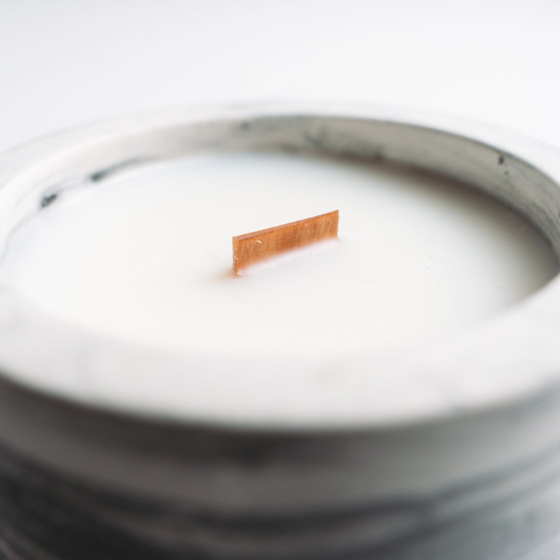 Marble-patterned candle with a wooden wick on a white background