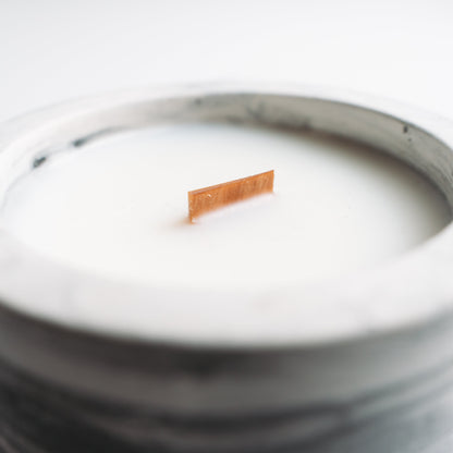 Marble-patterned candle with a wooden wick on a white background